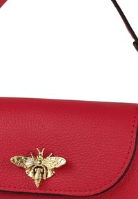 Rode lederen handtas met een gouden bij-versiering aan de voorkant. Het ontwerp heeft een klepafsluiting en contrasterende zwarte stiksels.