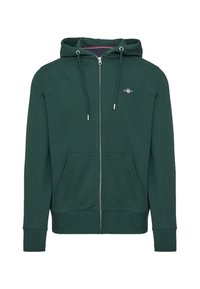 Grøn zip-up hættetrøje lavet af blødt stof, med en hætte, to forlommer og et lille logo på brystet. Syede manchetter og kant.