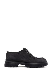 Zwarte suède schoenen met een ronde neus, leren accenten en een robuuste rubberen zool met diepe profiel. Drie grijzige veters zijn zichtbaar.