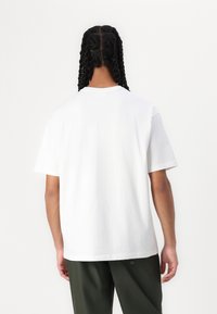 White short-sleeve t-shirt made of cotton. Features a crew neck, relaxed fit, and plain texture with no visible logos or patterns.