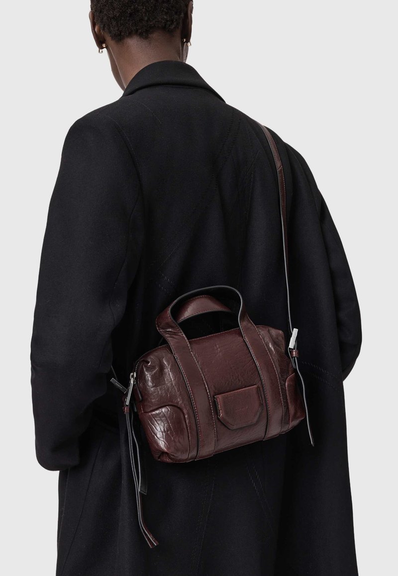 Mørkebrun læderhåndtaske med to top-hanke og en lang skulderrem, der har en struktureret overflade og en detalje med en forlomme.