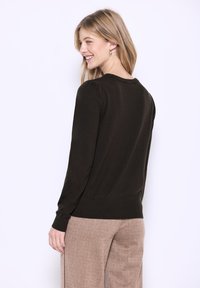 Dunkelgrüner Pullover mit langen Ärmeln, Rundhalsausschnitt, gerippten Bündchen und Saum. Er zeichnet sich durch eine glatte Oberfläche und eine figurbetonte Silhouette aus.