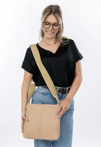 Borsa a tracolla beige realizzata in pelle texturizzata con una forma rettangolare semplice, dotata di una larga tracolla regolabile e dettagli di cucitura visibili.