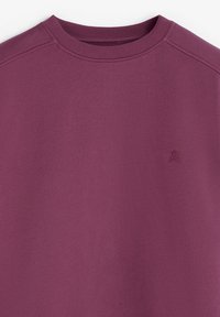 Sudadera morada con cuello redondo y tela texturizada. Exhibida sin mangas, con un sutil logo bordado en el pecho.