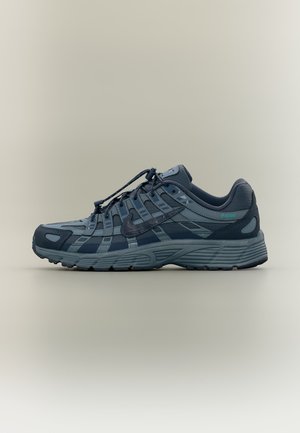 Ciemnoszare i czarne buty do biegania Nike z warstwowym designem, zapięciem na sznurówki i teksturowaną podeszwą na neutralnym tle.