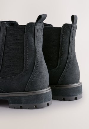 Zwarte Chelsea-laarzen met gestructureerd leer, elastische zijpanelen en een robuuste rubberen zool met een opvallend profiel.