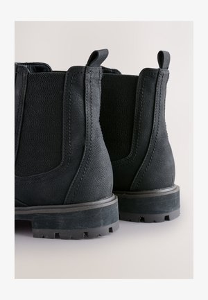Zwarte Chelsea-laarzen met gestructureerd leer, elastische zijpanelen en een robuuste rubberen zool met een opvallend profiel.