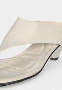 Mule couleur crème à bout ouvert avec semelle intérieure rembourrée, petit talon bloc et large bride sur le dessus.