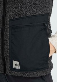 Fleecejacke mit einer schwarzen Reißverschlusstasche, grauem Strukturmaterial und einem North Bend-Logopatch. Weiches und lässiges Design.