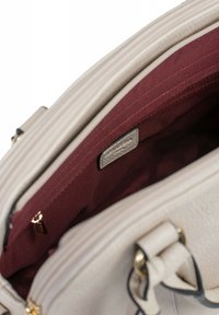 Borsa beige con una superficie esterna in tessuto sintetico testurizzato. Interno rivestito in tessuto bordeaux con una tasca con zip e un piccolo cartellino in metallo.