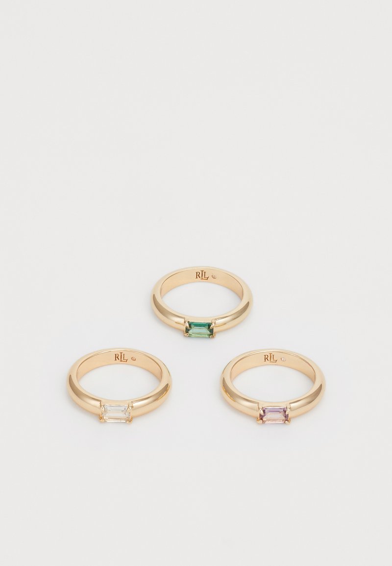 Tres anillos de oro con gemas rectangulares: una piedra clara, una verde y una rosa, engastadas en bandas suaves y redondeadas.