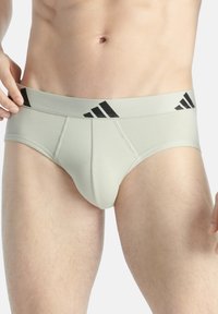 Ljusgrå, tajta boxershorts med ett svart randigt elastiskt midjeband som har Adidas-logotypen. Slät textur och skräddarsydd design för komfort.