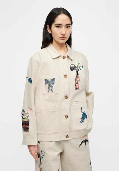 Μπεζ μπουφάν καμβά με διάφορα πολύχρωμα κεντήματα, που περιλαμβάνουν ζώα και λουλούδια, με κούμπωμα με κουμπιά και μπροστινές τσέπες.