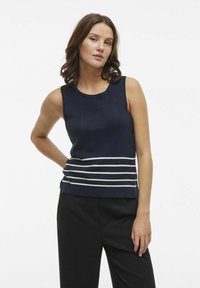Top senza maniche blu navy con texture a coste e righe bianche orizzontali all'orlo. Vestibilità sartoriale, abbinato a pantaloni neri.