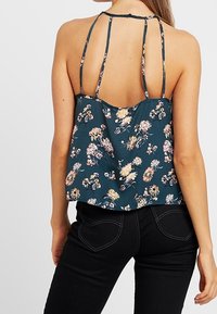 Blommig ärmlös topp i teal-färgad tyg med avslappnad passform, med tunna axelremmar och en baksidedetalj med justerbara band.