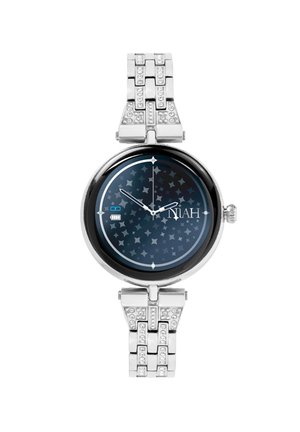 Montre en argent avec boîtier rond, cadran sombre à motif d'étoiles, marqueurs d'heure clairs et bracelet orné de cristaux. Indicateur de batterie visible.