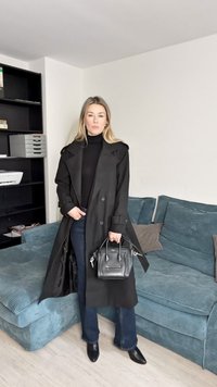 Fekete gyapjú ballonkabát dupla soros kialakítással, széles hajtókkal és sima textúrával, sötét farmerral és kis fekete kézitáskával párosítva.