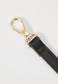 Correa de cuero negro con cierre de langosta en tono dorado y bucle de metal, con costuras detalladas a lo largo de los bordes. Textura suave.