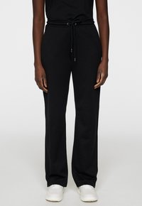 Svarta sweatpants med avslappnad passform, dragsko i midjan och sidofickor. Tillverkade av mjukt tyg med en slät yta.