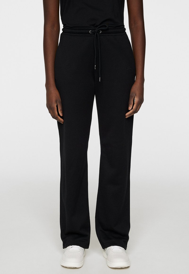 Svarta sweatpants med avslappnad passform, dragsko i midjan och sidofickor. Tillverkade av mjukt tyg med en slät yta.