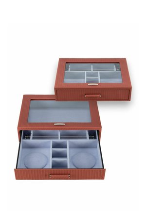 Deux boîtes à bijoux rouges texturées avec couvercles en verre, l'une ouverte montrant plusieurs compartiments et coussins en velours gris à l'intérieur.