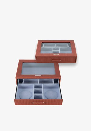 Deux boîtes à bijoux rouges texturées avec couvercles en verre, l'une ouverte montrant plusieurs compartiments et coussins en velours gris à l'intérieur.