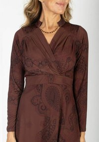 Brązowa sukienka z długim rękawem w wzór paisley, dekolt w serek i marszczenia na ramionach. Gładki, dopasowany materiał z eleganckim układem.