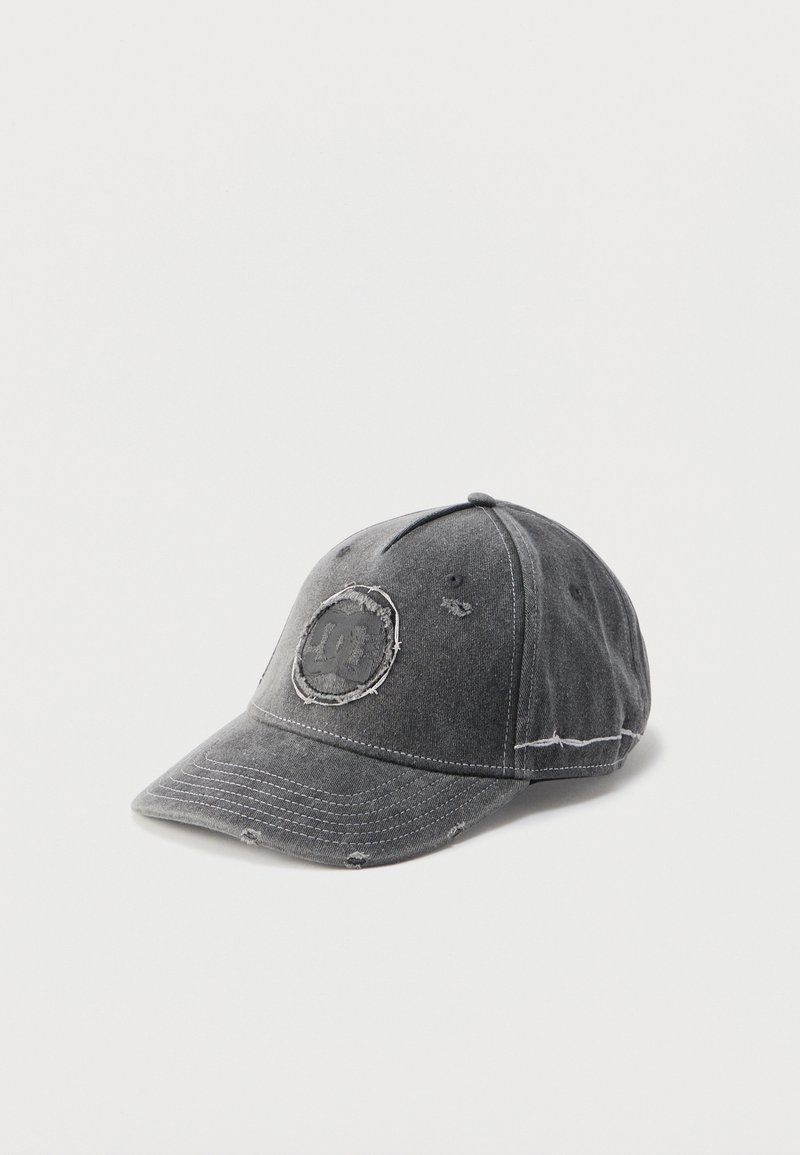 Casquette de baseball gris foncé avec des détails usés et un patch circulaire cousu ornant un visage souriant délavé sur le panneau avant.