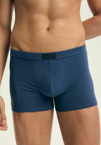 Granatowe męskie bokserki wykonane z elastycznej tkaniny. Posiadają miękki, elastyczny pas i dopasowany krój. Prosta, gładka faktura.