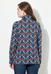 Langärmliges Hemd mit hohem Kragen, verziert mit einem floralen Muster in Blau, Pink und Grün auf schwarzem Hintergrund. Glatte Stoffoberfläche.