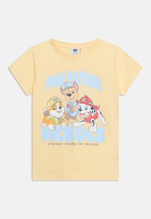 Gul t-shirt med tre hunde fra Paw Patrol iført hjelme og uniformer, med teksten "Paw Patrol-helte altid klar til redning."