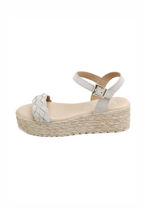 Sandalia de plataforma beige con tira frontal trenzada, correa al tobillo con hebilla dorada y suela con textura tejida.