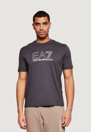 Maglietta grigia in cotone con maniche corte, con il logo bianco "EA7 Emporio Armani" ben visibile sul davanti. Tessuto morbido e vestibilità regolare.