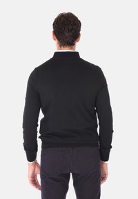Maglione lavorato a maglia nera con collare alto, polsini e orlo a costine. Design semplice, senza motivi visibili o componenti metallici.