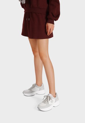 Scarpe sportive grigio chiaro con tomaia in suede e tessuto testurizzati, dotate di suole e lacci bianchi, abbinate a una gonna bordeaux.