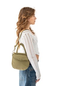 Zelená prešívaná ramenná taška s hornou rukoväťou a nastavitelným popruhom, vystavená na modeli, s minimalistickým dizajnom a mäkkou textúrou.