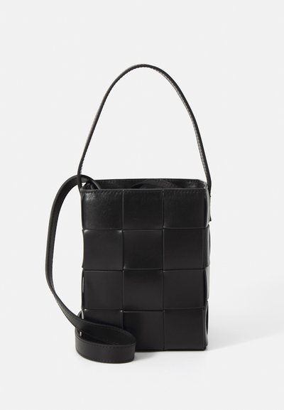 Bolso de cuero negro con diseño trenzado. Forma rectangular, con asa corta y correa ajustable. Textura suave con un acabado mate.