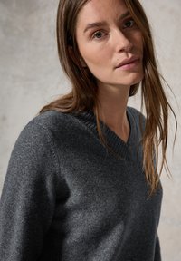 Dunkelgrauer Wollpullover mit V-Ausschnitt und strukturiertem Finish, ausgestattet mit einem gerippten Detail am Kragen und an den Ärmeln für eine enganliegende Passform.