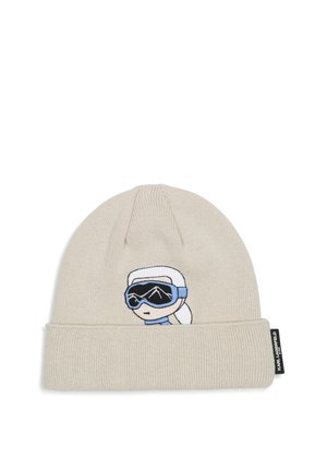 Bonnet en tricot beige clair avec bord replié et visage de dessin animé brodé portant des lunettes de ski et un foulard blanc.