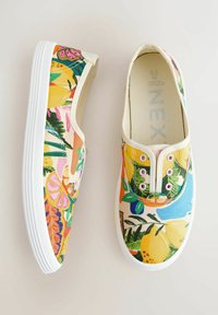 Trampki wsuwane z jasnym, wielokolorowym wzorem tropikalnych owoców i liści, wyposażone w białe podeszwy i elastyczne przelotki ułatwiające zakładanie.