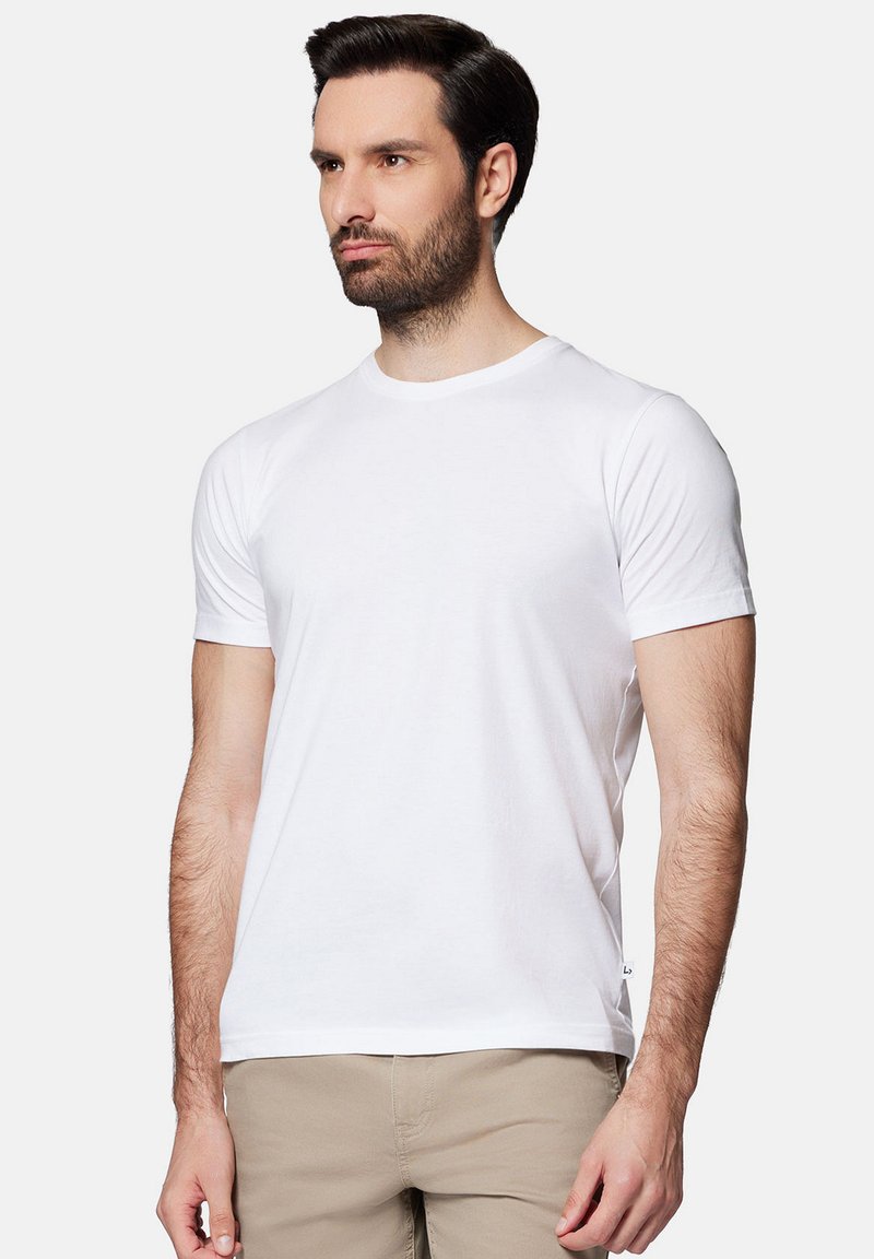 Biała koszulka z krótkim rękawem o okrągłym dekolcie, wykonana z materiału bawełnianego, z delikatną fakturą i małą metką z logo z boku.