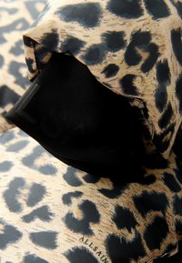 Leopardprint stof i beige og sort med en blød tekstur og glat overflade. Inkluderer et sort mærke med brandnavnet synligt.