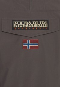 Šedá látka s výraznou černou a béžovou nášivkou s logem "Napapijri" a červeno-modrou vyšívanou norskou vlajkou.