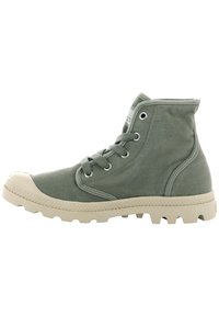 Bottines de cheville en toile verte avec un capuchon en caoutchouc et une semelle texturée blanche. Présente des œillets en métal et des détails de couture contrastants.