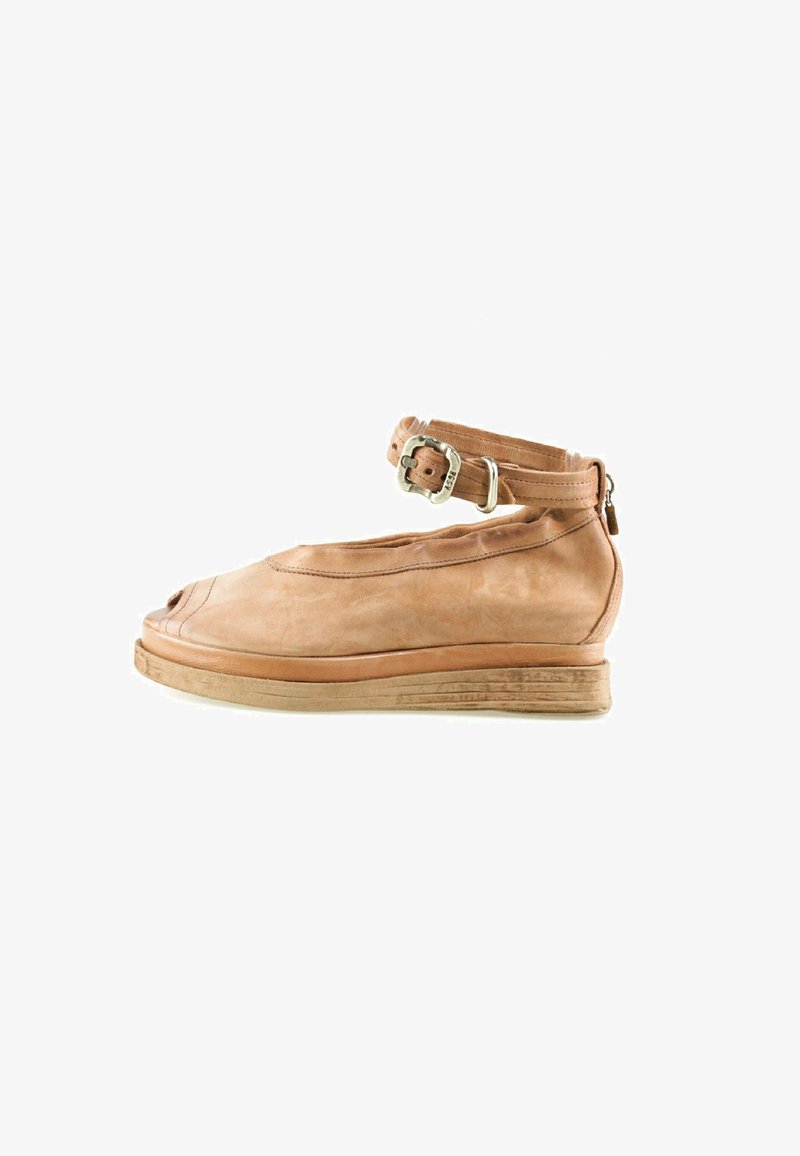 Chaussure montante en cuir marron clair avec orteils ouverts, semelle épaisse et bride réglable avec boucle argentée autour de la cheville.