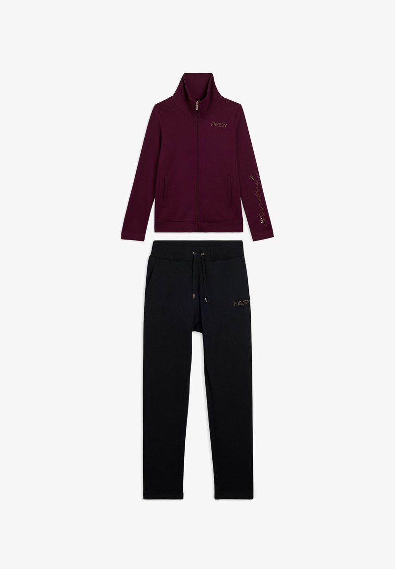 Giacca bordeaux con zip e colletto alto, abbinata a pantaloni neri con cordoncino, entrambi decorati con il logo "FREDDY" in lettere dorate.