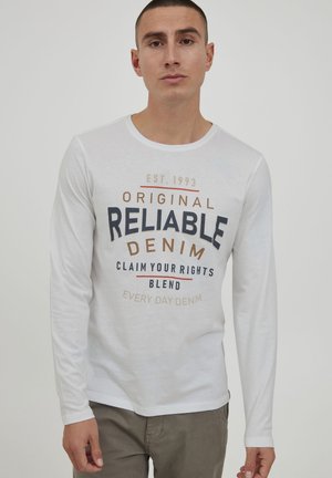 White long-sleeve T-shirt with a round neck, featuring multicolored text graphic: "Original Reliable Denim" and additional phrases in various colors.
