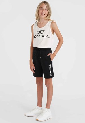 Biely tielko s čiernym logom O'Neill, kombinované s čiernymi šortkami s bočným logom. Biely tenisový obuv s hnedými podrážkami dotvára vzhľad.