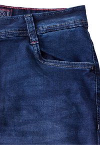 Mörkblå denimjeans med en klassisk femfickdesign, synliga sömmar och en röd detalj på midjebandet.