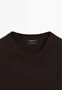 Maglione in cashmere marrone scuro con scollatura rotonda e colletto a coste. L'etichetta interna riporta "Massimo Dutti, 100% cashmere." Texture morbida.